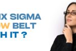 A thoughtful-looking woman with glasses, dressed in black, poses against a white background. Bold text on the left reads: “IS A SIX SIGMA YELLOW BELT WORTH IT?” with “YELLOW BELT” highlighted in yellow. Zabeel Institute logo is at the top left, and the website link https://zabeelinstitute.ae/ appears at the bottom.