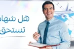 رجل مبتسم يحمل ملفاً في يده مع خلفية تضم خريطة العالم وطائرات وسفن وشاحنات – هل شهادة CIPS تستحق؟ – زعبيل للتدريب في دبي