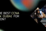 A promotional banner with a dark background and a vibrant, colorful abstract pattern on the top. The left side of the banner features the logo for "ZABEEL INTERNATIONAL INSTITUTE OF MANAGEMENT & TECHNOLOGY" and the question "WHICH IS THE BEST CCNA TRAINING IN DUBAI FOR CERTIFICATION?" in large, white text. At the bottom left, the website "https://zabeelinstitute.ae/" is displayed. The right side of the banner has a photograph of a smiling woman holding a tablet. She is reflected in a large laptop screen, which displays a digital interface with a lock icon and various data. The image is cropped in a striking, diamond-like shape. The overall design is modern and focuses on technology and cybersecurity.
