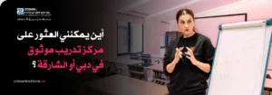 مدرس/مدرب يقدم دورة تدريبية أو ورشة عمل في مجال المحاسبة والمالية في دبي أو الشارقة. تُظهر الصورة امرأة ترتدي قميصًا أسود وهي تشرح على لوح أبيض في قاعة دراسية. النص العربي على الصورة يسأل: "أين يمكنني العثور على مركز تدريب موثوق في دبي أو الشارقة؟" مع شعار "Zabeel International".