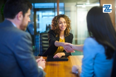 A woman and a man shaking hands in a modern office setting, symbolizing a professional agreement or partnership.